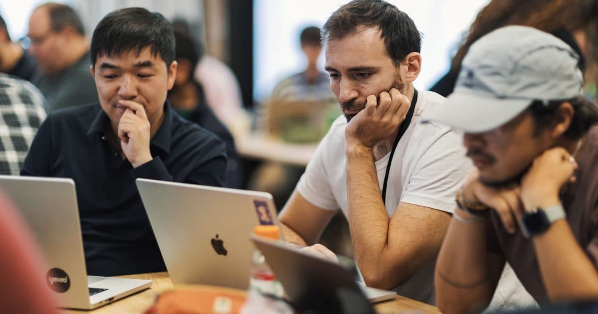 Diverse team of professionals collaborating on laptops while evaluating an AI agent workflow