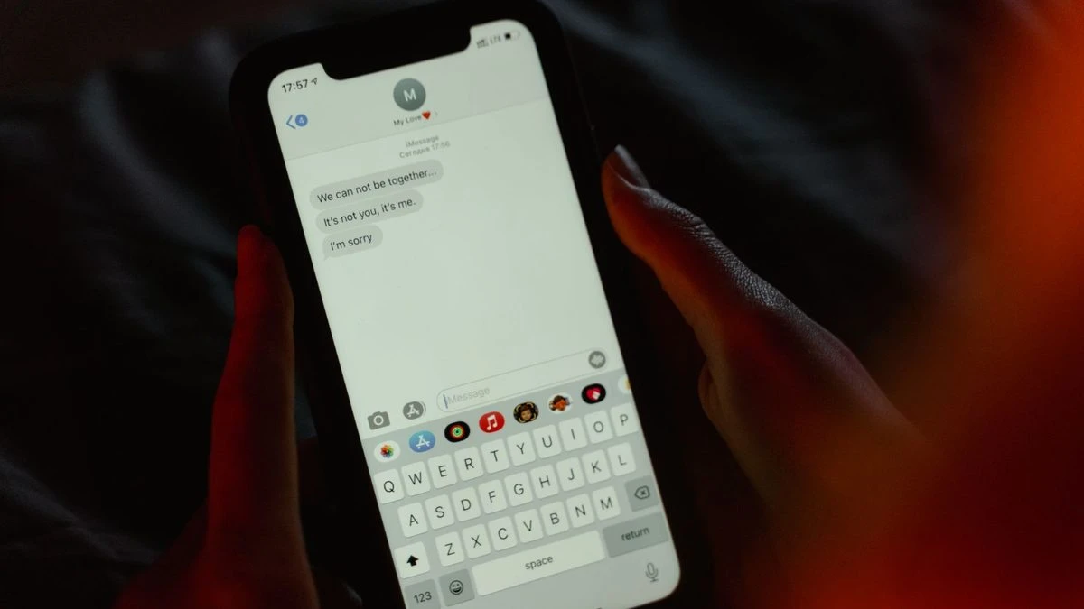 Close-up of a breakup message on a smartphone screen, held in hands, evoking emotions.