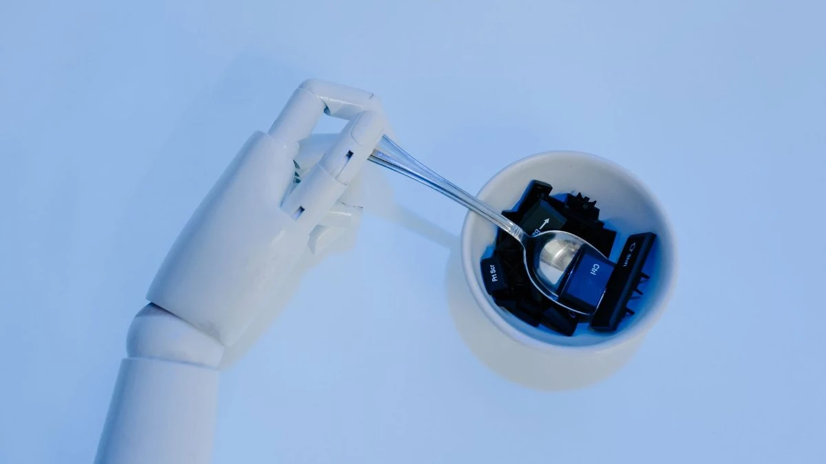 A robotic hand holds a spoon filled with keyboard keys, symbolizing AI and technology fusion.