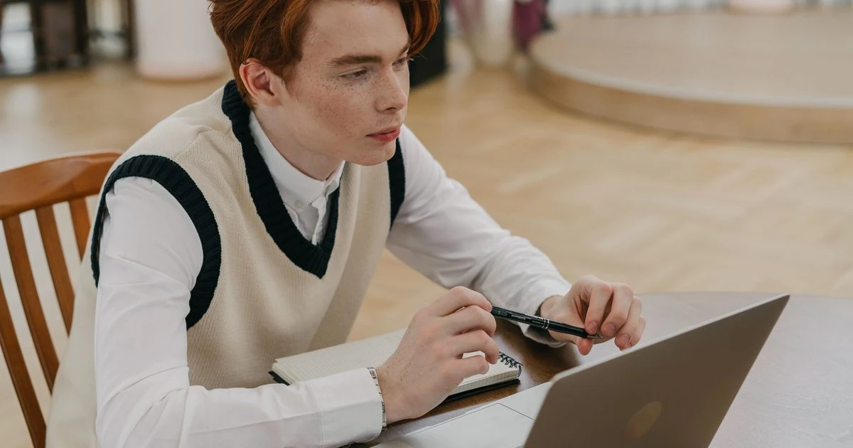 Beginner learning AI online at home with a laptop and notebook.