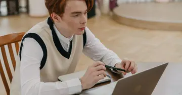Beginner learning AI online at home with a laptop and notebook.