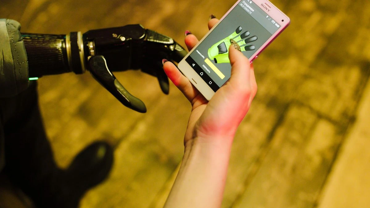 A close-up of a prosthetic hand interacting with a smartphone showcasing futuristic technology.