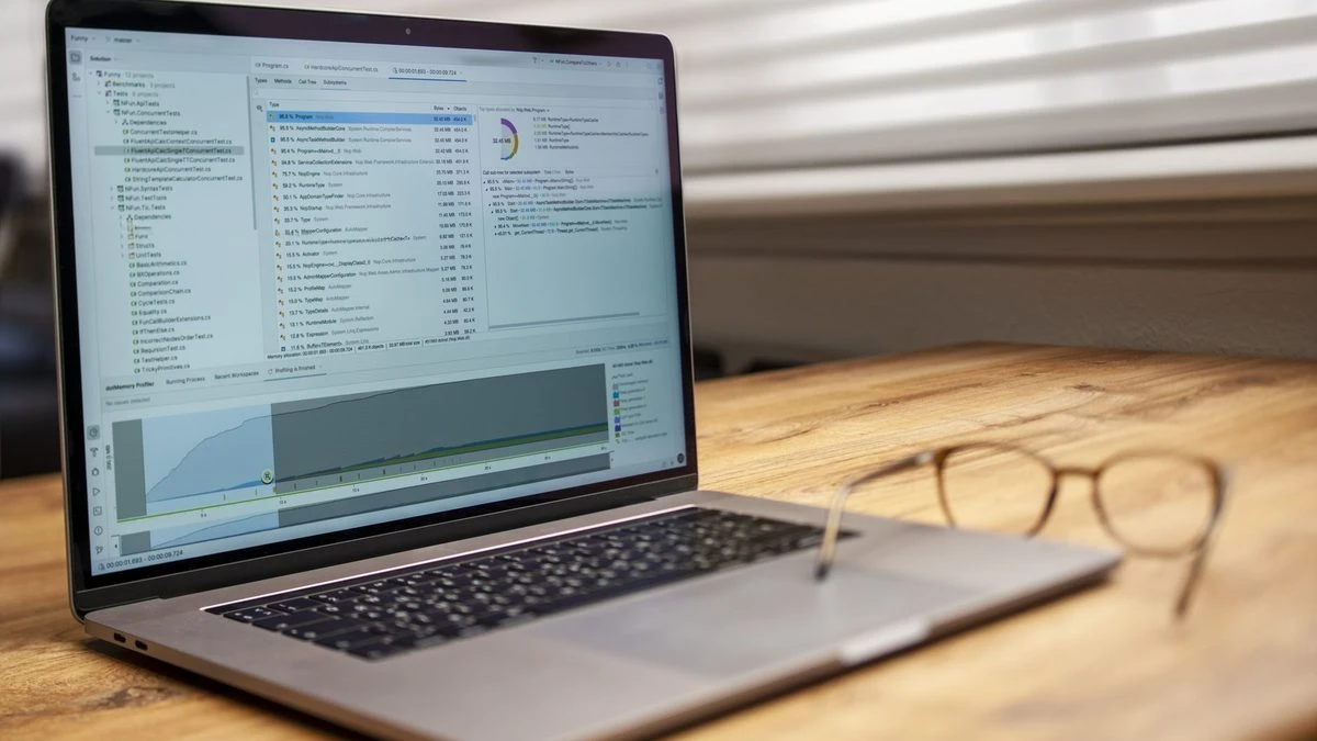 Modern laptop on a wooden desk displaying analytical software with eyeglasses nearby, indoor shot.