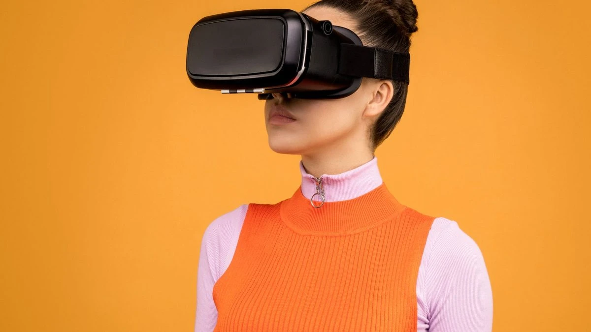 Woman enjoying virtual reality with VR headset against vibrant orange background.