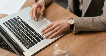 Beginner building a first AI agent without code on a laptop at a wooden desk.