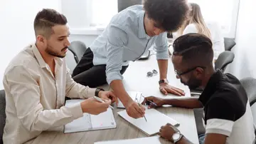 A diverse team of professionals collaborating in a modern office setting, focusing on brainstorming and planning.