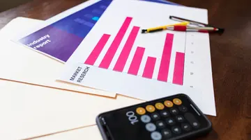 Illustrative market research chart and calculator on wooden desk for business analysis.