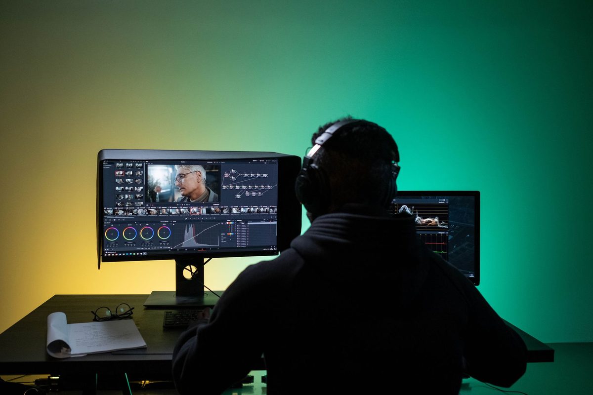 Video editor finishing an AI-generated clip on dual monitors with headphones